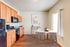 Inviting kitchen and dining area featuring warm wooden cabinetry, sleek black appliances, and abundant natural light through large windows.