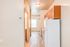 Bright apartment hallway with modern wood flooring, leading to a cozy kitchen and entrance to a well-lit bathroom.