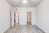 Bright, spacious room with sleek wood flooring, white walls, and modern ceiling fan; two open doors leading to a walk-in closet and hallway, ideal for a serene living space.