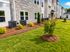 Elegant apartment complex with stone and siding exterior, surrounded by lush green landscaping and neatly arranged shrubs.
