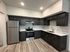 Modern kitchen with sleek dark cabinetry, stainless steel appliances, and elegant wood flooring.