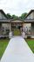Inviting apartment complex entrance with modern stone pillars, lush greenery, and a welcoming walkway.