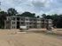 Newly constructed 3-story apartment building with modern design surrounded by lush greenery and blue skies.