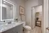 Elegant bathroom featuring a modern illuminated mirror, sleek vanity, and spacious storage area with natural decor.