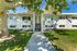 Charming mid-century apartment complex with decorative latticework, lush green lawn, and mature shade trees.