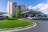 Modern apartment building with covered parking, lush green landscaping, and clear blue skies.