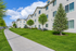 Charming apartment building with manicured lawns and vibrant trees against a blue sky, ideal for tranquil living.