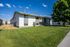 Charming apartment building with large windows and lush green lawn under a clear blue sky, ideal for comfortable living.