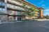 Modern apartment building exterior showcasing spacious balconies and convenient carport parking, set against a clear blue sky.
