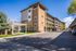 Modern apartment building with stunning mountain views, offering ample parking and a charming outdoor seating area.