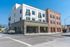 Charming modern apartment building on a sunny corner, featuring elegant design with large windows and a clean facade.