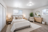 Bright and spacious bedroom with a plush queen bed, stylish wooden furniture, and elegant decor, featuring large windows that fill the room with natural light.