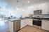 Modern kitchen with sleek appliances and open dining area leading to a bright living space.