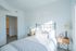 Bright and airy bedroom with elegant metal bed frame, cozy linens, and inviting natural light, perfect for relaxation.