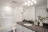 Modern bathroom with sleek black countertop, elegant faucet, and bright lighting; featuring a stylish bathtub and decorative plants.