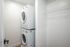 Sleek laundry nook featuring a stacked washer and dryer with spacious shelving for your convenience.