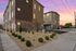 Modern townhouse exterior at sunset showcasing stylish stone facade, lush landscaping, and elegant architectural design.