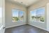 Bright room with large windows showcasing a stunning mountain and suburban view, featuring modern wood flooring and soft neutral walls.