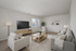Modern living room featuring elegant neutral decor, plush seating, and a large flat-screen TV.