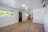 Bright open-plan living area with modern wood flooring, stainless steel appliances, and large windows offering natural light.