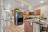 Inviting kitchen with elegant wooden cabinetry, sleek black appliances, and a cozy breakfast bar accented with wine and fruit decor.