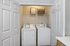 Charming laundry nook with modern washer and dryer, accented by a decorative basket and inspirational wall art.