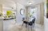 Bright and elegant dining area with a modern glass table and chic decor leading to a cozy, inviting living room with stylish accents.