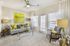 Bright and modern living room with elegant decor, featuring a cozy sofa, chic armchair, and vibrant artwork, complemented by large windows and natural light.