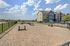 Pet-friendly apartment complex featuring a spacious fenced dog park with agility equipment and stunning blue skies.