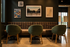 Chic and cozy seating area with stylish green chairs, plush brown banquette, and vintage wall art creating an inviting ambiance.