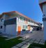Modern apartment complex with sleek design, vibrant orange accents, and spacious balconies under a clear blue sky.