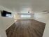 Inviting living room with elegant wood flooring, large windows, and a ceiling fan for a bright, airy ambiance.