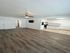 Modern open-concept living area with sleek hardwood floors, ceiling fan, and a bright kitchen with white cabinetry.