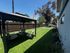 Inviting outdoor space with cozy seating under a gazebo, surrounded by lush greenery and vibrant plants, perfect for relaxation and entertainment.