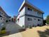 Modern apartment complex with vibrant orange accents, showcasing spacious outdoor areas and sleek design in a sunny setting.