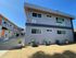 Bright and modern apartment complex with stylish orange accents, lush planters, and a prominent leasing sign, offering an inviting residential option.