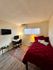 Cozy bedroom with a vibrant red bed, elegant rug, and a functional study corner with a modern desk.