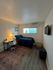 Cozy bedroom with a modern workspace, featuring a comfortable bed, stylish desk, and soft lighting in a serene atmosphere.
