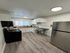 Modern kitchen with sleek stainless steel appliances, cozy dining nook with bar stools, and stylish wood flooring.