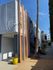 Modern apartment building with vibrant orange accents and a charming exterior stairway, complemented by a sunny courtyard and tall palm tree.