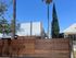 Modern apartment complex 'The Arches' highlighted by sleek wooden fencing and towering palm trees under a vibrant blue sky.