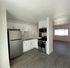 Modern kitchen with sleek stainless steel appliances, white cabinetry, and open layout leading to spacious living area with abundant natural light.
