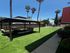 Charming outdoor space featuring a cozy seating area under a gazebo, surrounded by lush green grass and towering palm trees.
