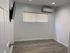 Bright, modern bedroom with sleek laminate floors, wall-mounted TV, and efficient air conditioning unit.