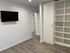 Modern apartment interior showcasing a sleek wall-mounted TV, elegant built-in shelving, and contemporary wood flooring for a sophisticated living space.
