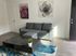 Modern living room with a sleek gray sofa, chic abstract wall art, and a stylish black coffee table on a vibrant blue rug.