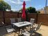 Inviting outdoor patio featuring a stylish dining set with a red umbrella, perfect for relaxing under the sun.