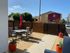 Inviting outdoor patio with elegant dining set and vibrant red umbrella in a sunny suburban setting.