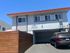 Charming apartment building with modern architectural design, featuring a covered parking area and eye-catching wood paneling.