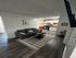 Cozy living room with stylish gray sofa, elegant striped rug, and modern open kitchen area.